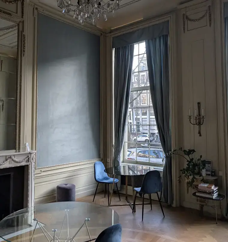 Salon van het Franchise-starten.nl kantoor aan de Herengracht 280 in Amsterdam met blauwe stoelen, glazen tafel en uitzicht op de gracht
